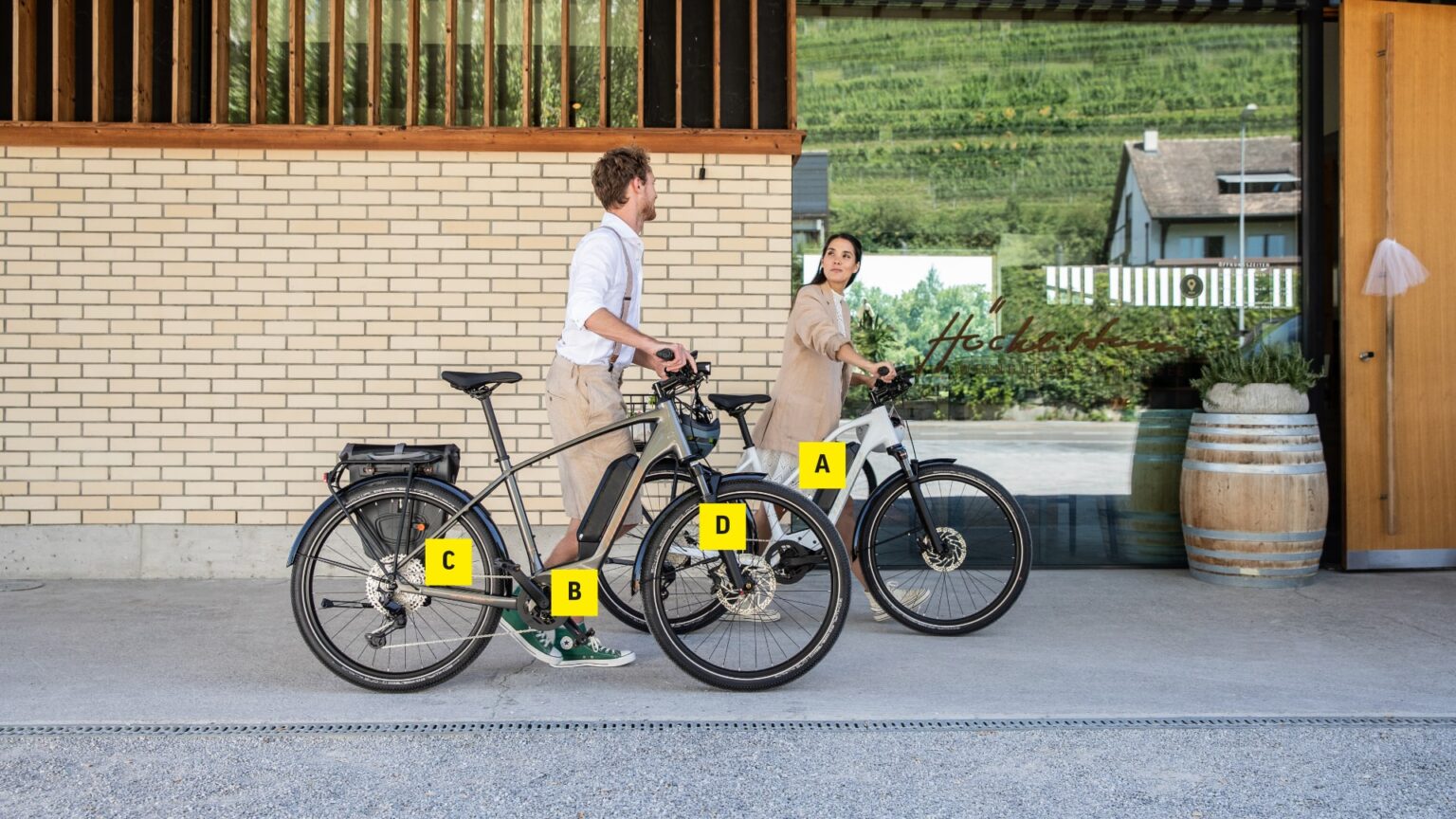 Zwei Personen neben E-Trekkingbikes vor einem Gebäude, ideal zur Orientierung und Beratung beim Kauf.