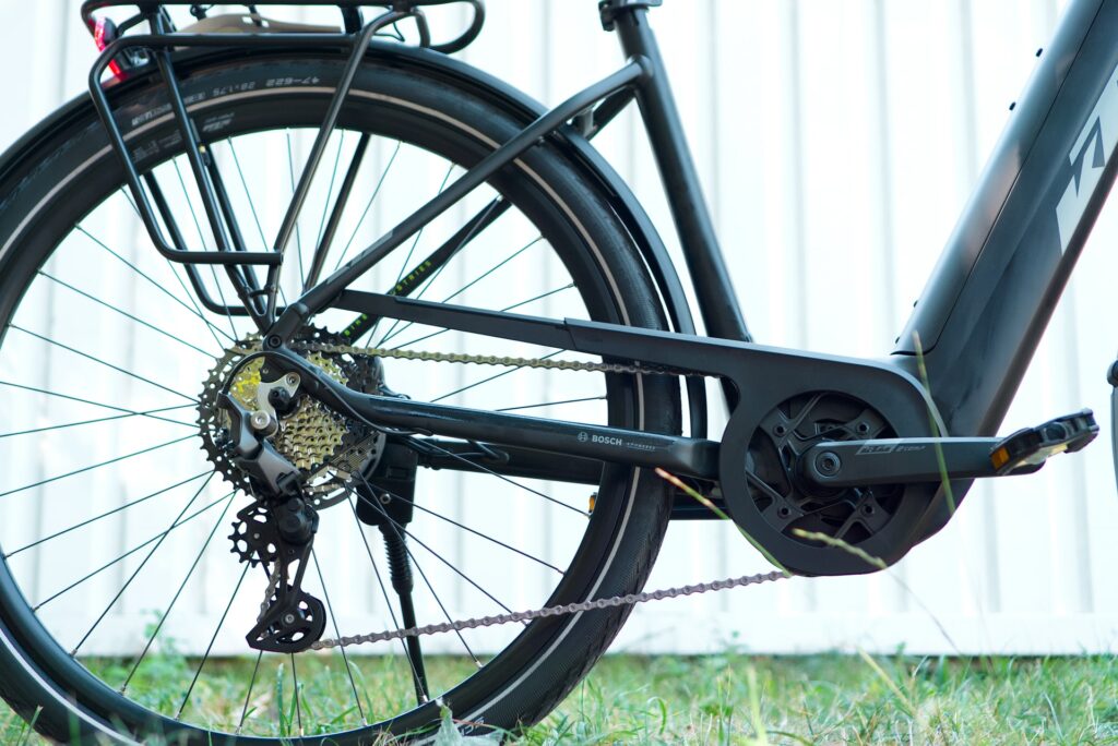 KTM Macina Style Pro 2024: Detailansicht des Bosch-Antriebs mit Kettenschaltung und Hinterrad im Fokus.