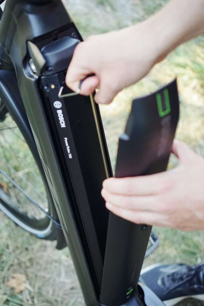 Bosch Powertube 750 Akku wird in das KTM Macina Style Pro 2024 E-Bike eingesetzt, Nahaufnahme der Hand.