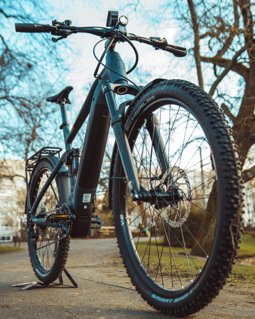 Axess Rogue FS Allroad 2024 Fahrrad auf Parkweg, robustes Design, breite Reifen, ideal für vielseitige Outdoor-Abenteuer.