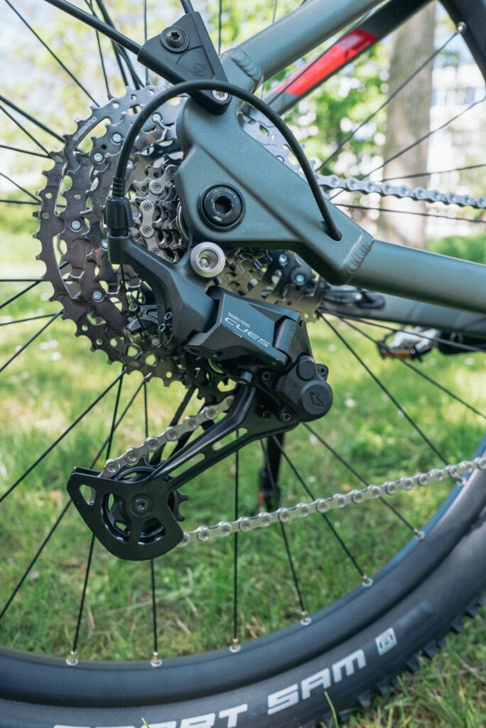 Shimano CUES Schaltwerk am Axess Force Pro Allroad Fahrrad, Nahaufnahme der Kettenschaltung im Grünen.