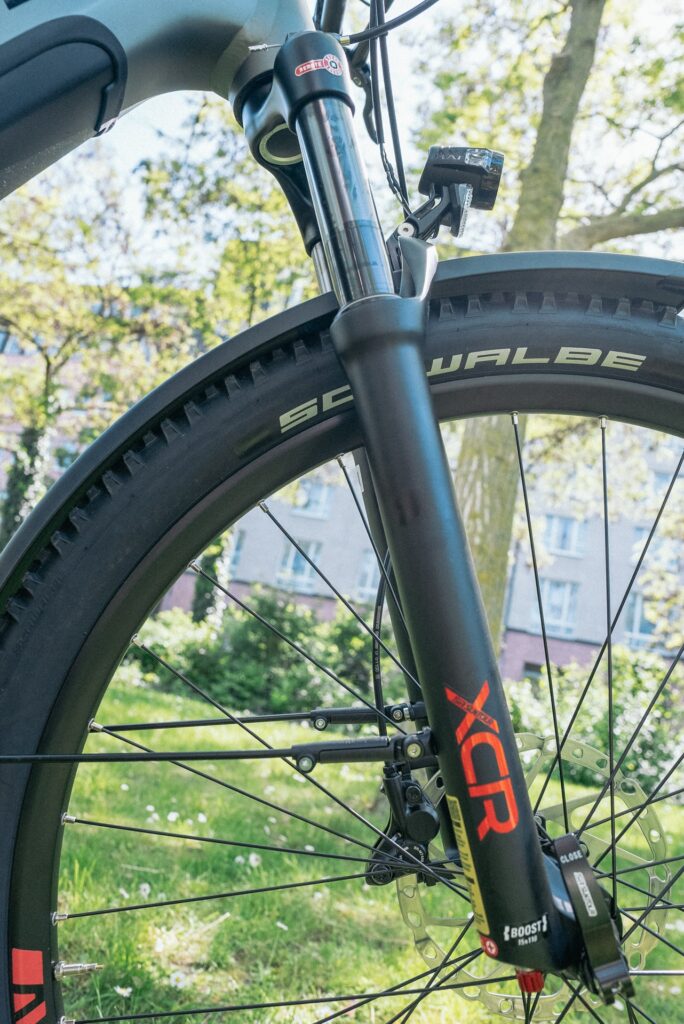 Suntour XCR-Federgabel und Schwalbe-Reifen eines Axess Force Pro Allroad im Grünen.