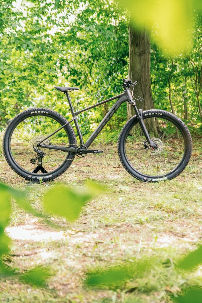 Scott Scale 980 2024 im Wald, seitlich, betont leichtes Design und robuste Reifen für Offroad-Abenteuer.