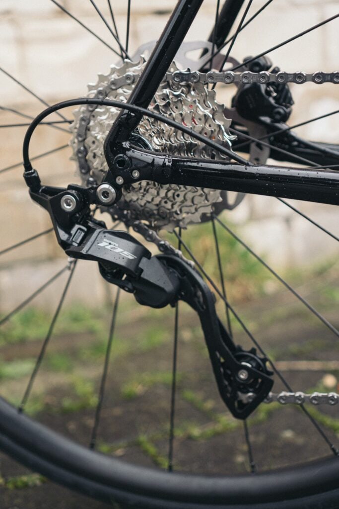Shimano 105 Schaltwerk an Trek Rennrad, Detailansicht der Gangschaltung und Kette bei nassem Wetter.
