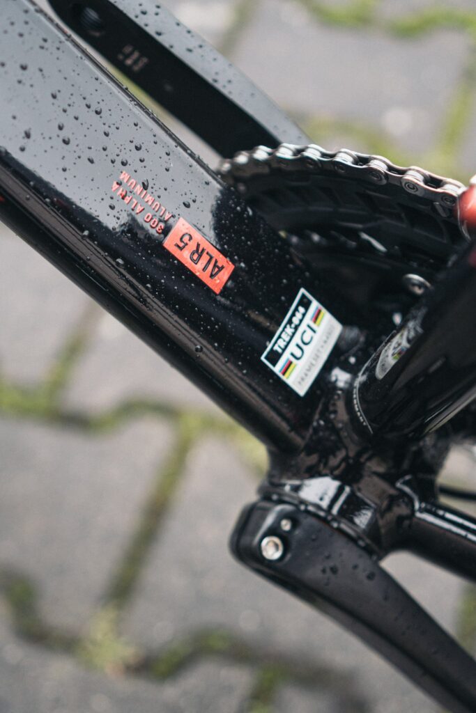 Nahaufnahme des Trek Émonda ALR 5 Rahmens mit 300 Alpha Aluminium und UCI-Zertifizierung bei nassem Wetter.