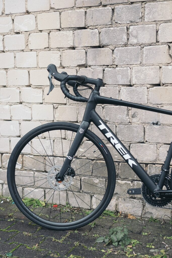 Trek Rennrad vor Ziegelwand, Fokus auf Vorderrad und Rahmen, ideal für Straßenrennen und sportliche Touren.