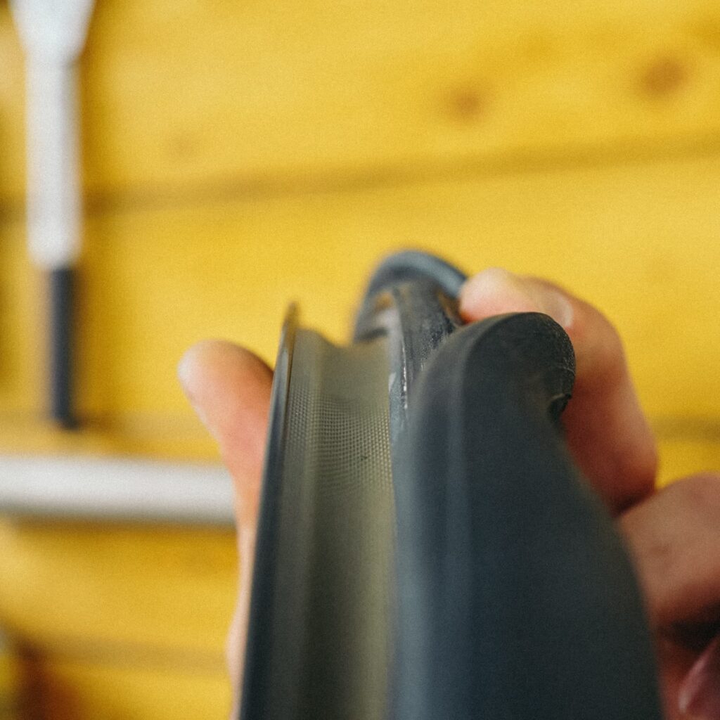 Nahaufnahme einer Hand, die einen Fahrradreifen hält, um einen Schlauch zu reparieren oder zu tauschen.