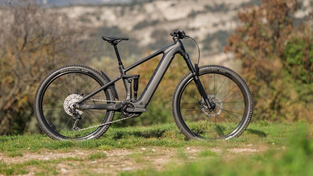 Cube Stereo Hybrid 2025 Modell auf grünem Gelände, seitliche Ansicht, Fokus auf Rahmen und Reifen.