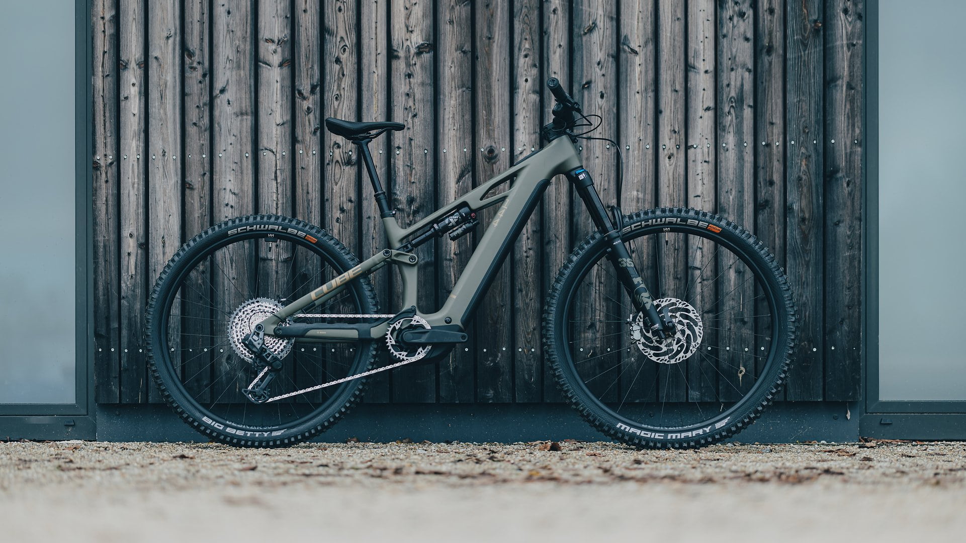 Cube Stereo Hybrid 2025 Modell vor Holzwand, seitliche Ansicht