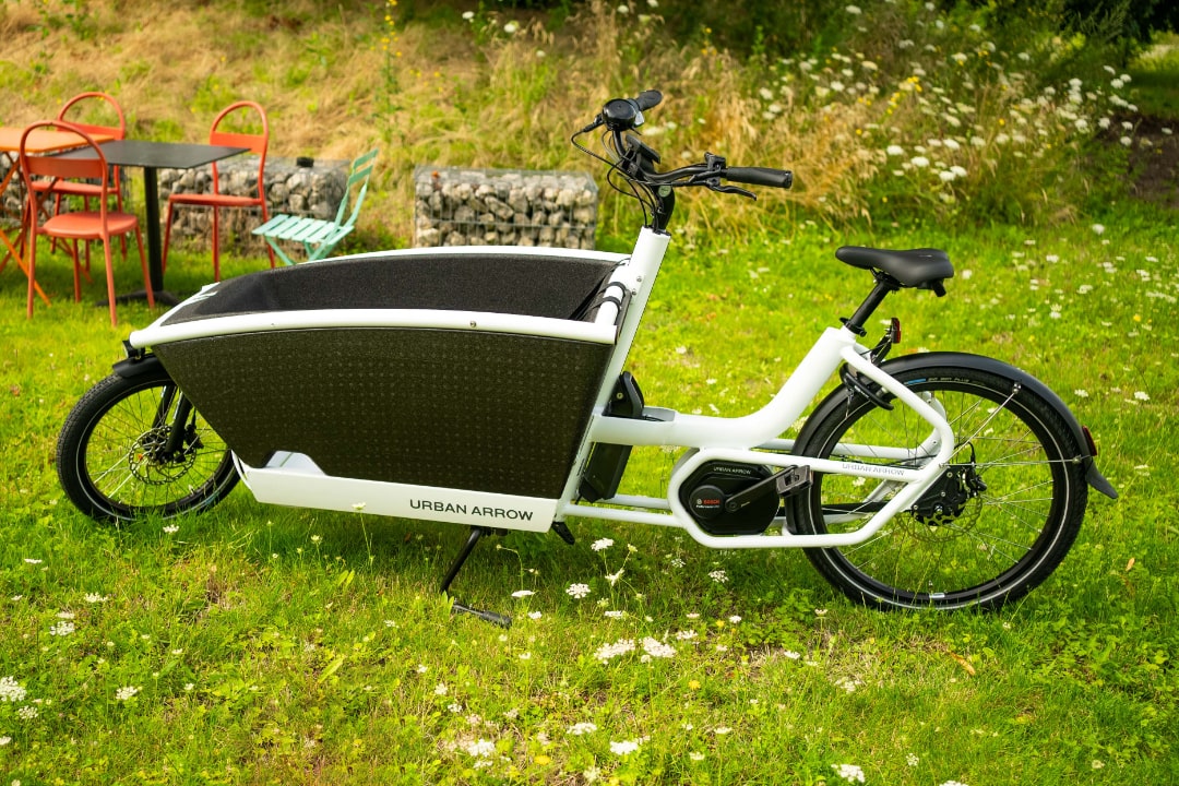 E-Lastenrad Urban Arrow Family im Grünen, ideal für umweltfreundlichen Transport in der Stadt.