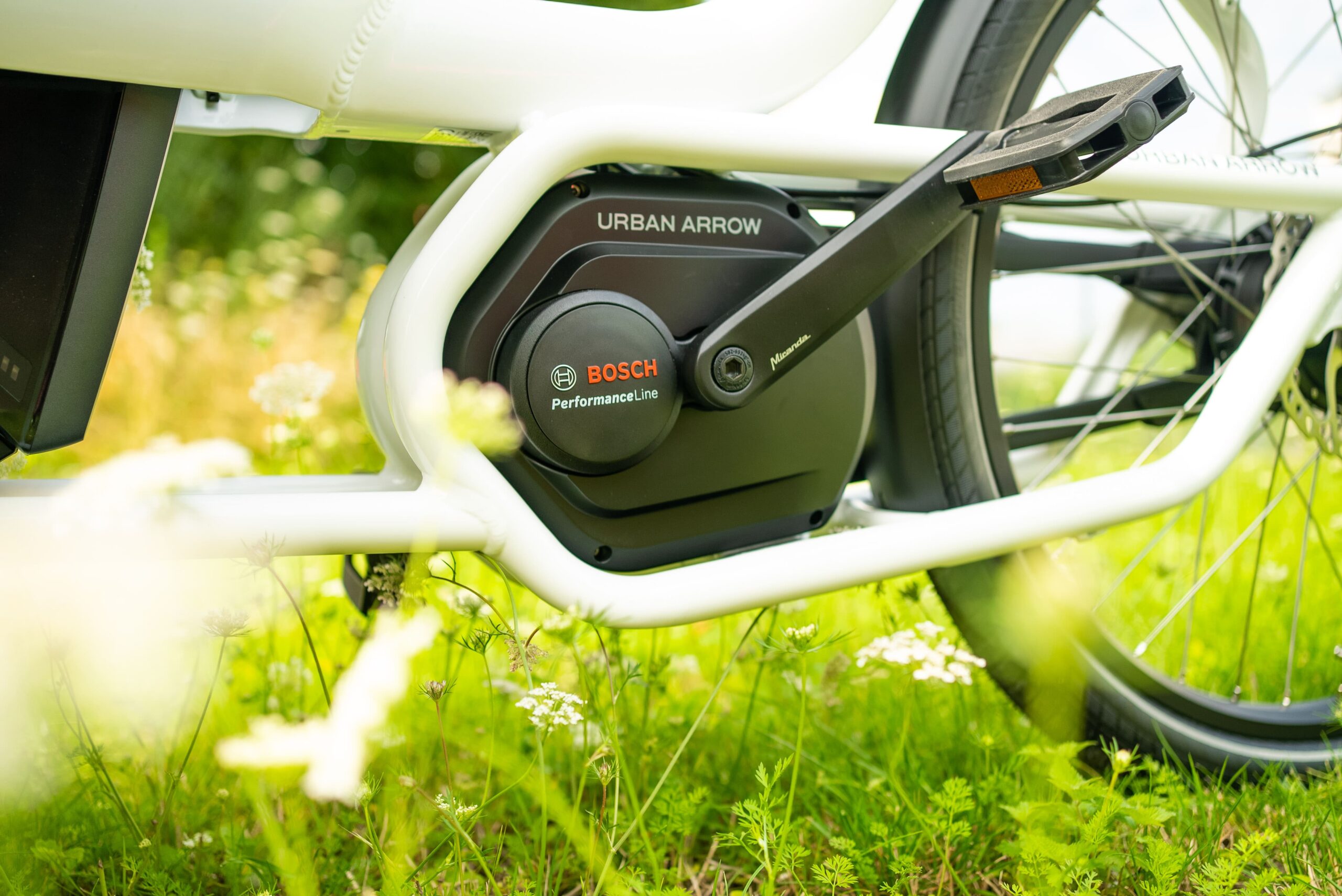 Bosch Performance Line Motor eines Urban Arrow E-Lastenrads, umgeben von grüner Wiese, für Kaufberatung vorgestellt.