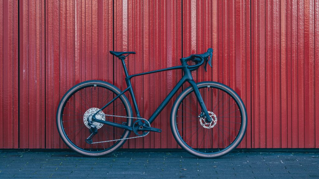 Cube Nuroad C:62 Fahrrad vor roter Wand, seitliche Ansicht.