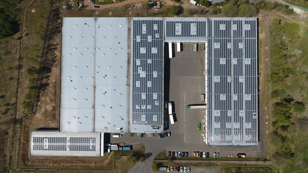 Blick vom oben auf das Dach des Lagers Rossau von Lucky Bike. Das Dach ist zum großen Teil mit Photovoltaik bedeckt.