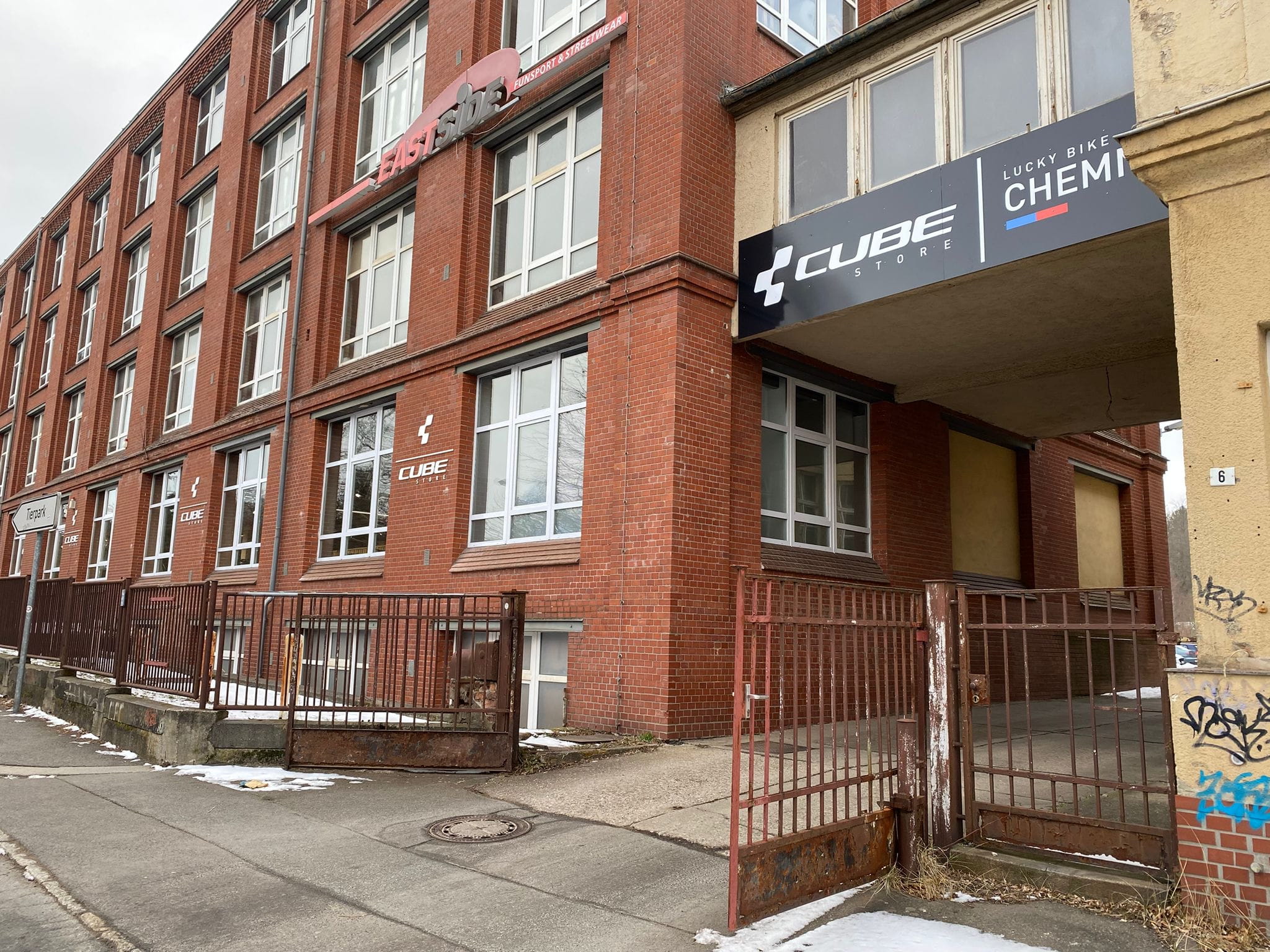 Außenansicht auf ein Gebäude mit roten Steinen. Über eine Hausdurchfahrt ist das Schild für den Cube Store Chemnitz.