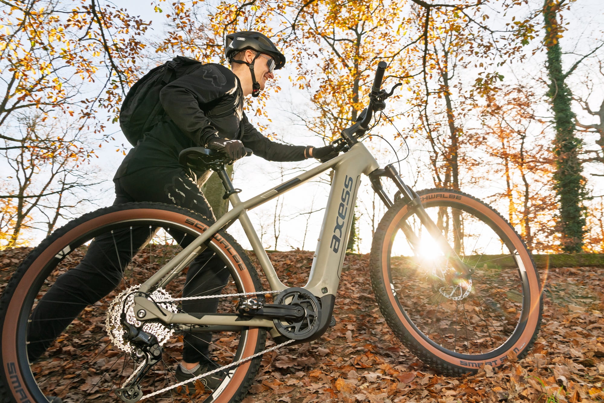 Ein Mann schiebt sein E-MTB einen Anstieg im Wald bei leichter Dämmerung hoch